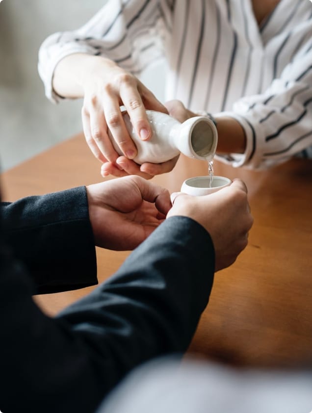A woman pouring Sake into a mans cups