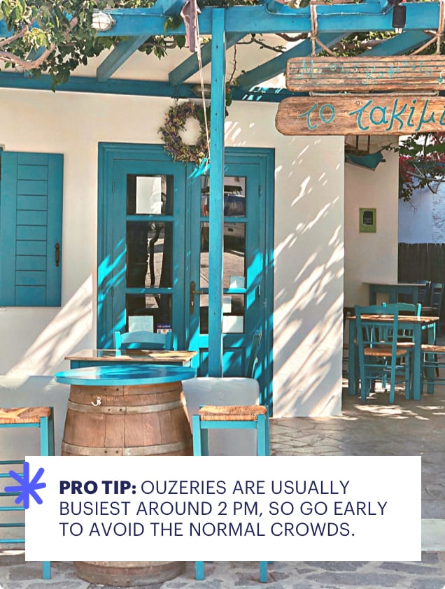 Outdoor seating area with blue chairs and tables in front of a building with a sign, featuring a tip about ouzeries.