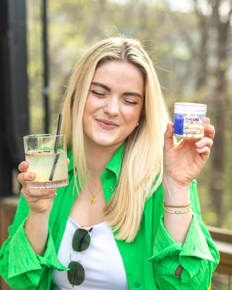 A woman holding a cocktail and Cheers restore
