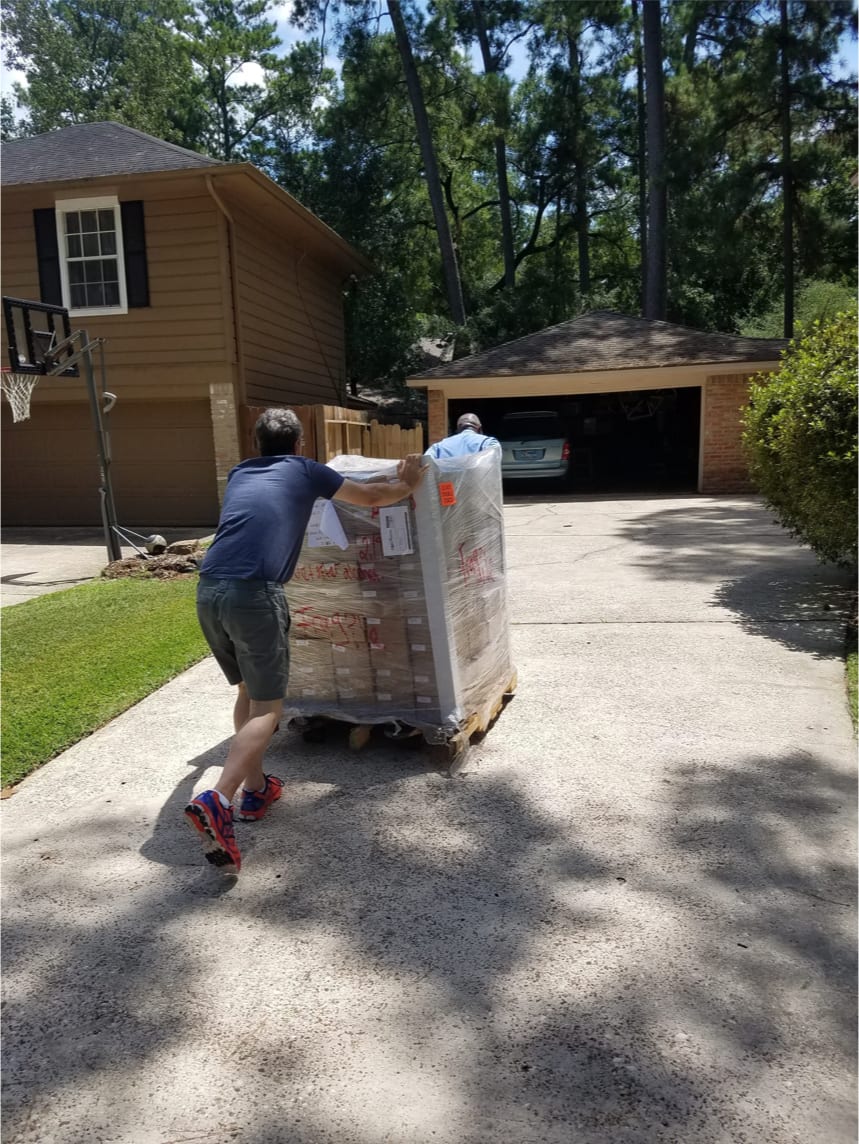 Man pushing a cart with boxes towards a house