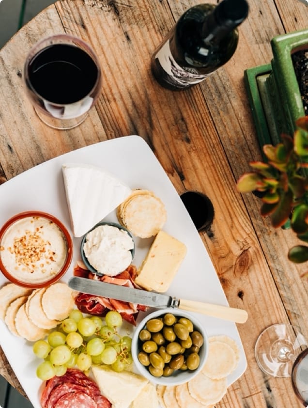 Assorted cheese and cracker platter with wine on a wooden table